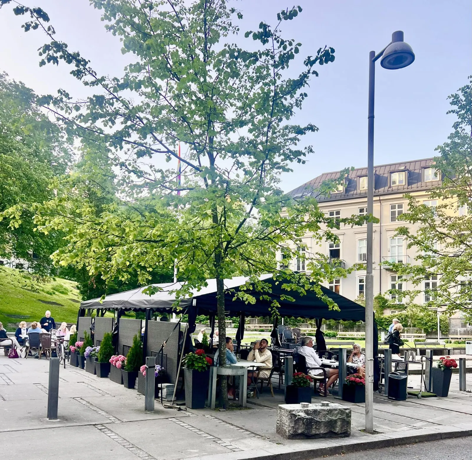 Uteserveringen vår i Pilestredet Park en sommerkveld, med gjester under telttaket